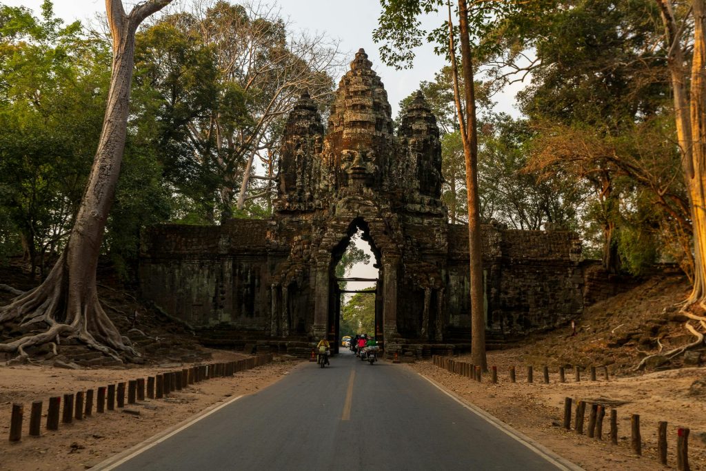 Explore the ancient South Gate of Angkor Thom amid a serene sunset setting in Cambodia's breathtaking jungle landscape.