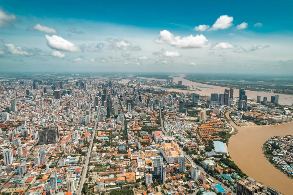 Stunning aerial view of Phnom Penh's skyline along the river under a blue sky.